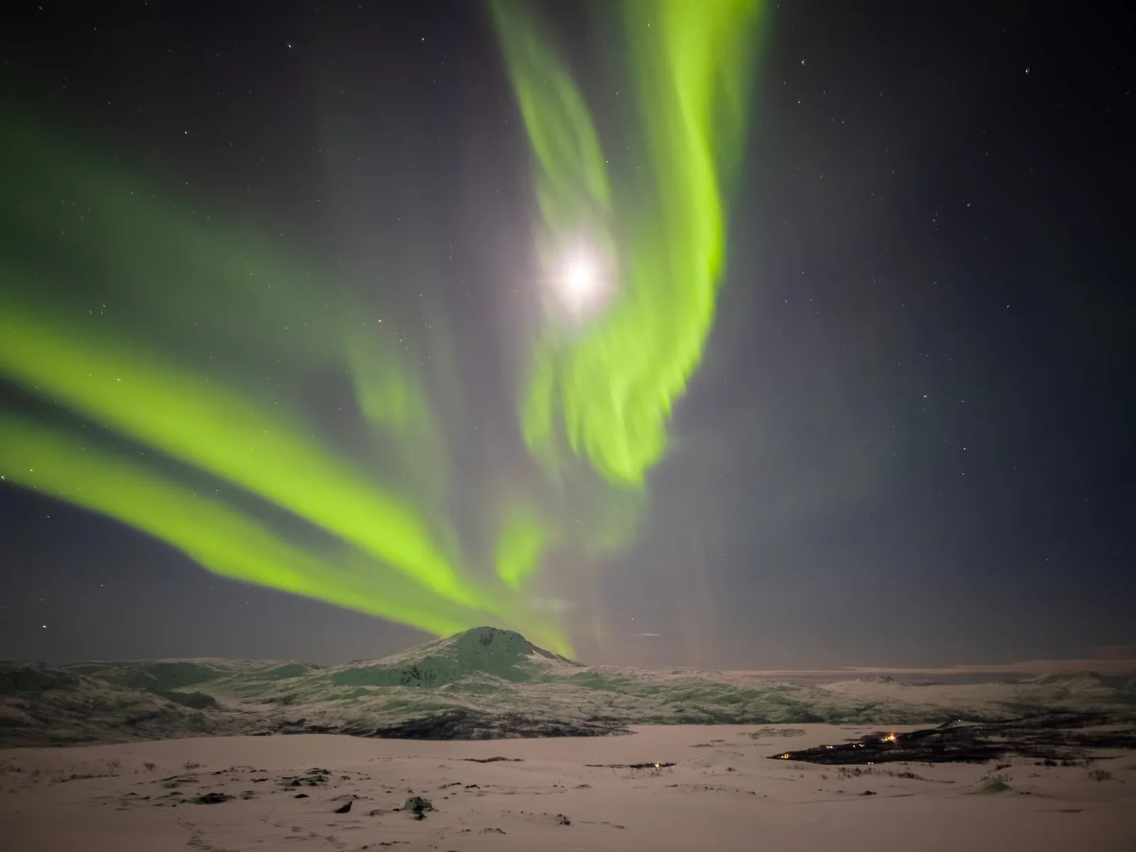 Aurore boréale au-dessus d'un fell enneigé de Laponie, la lune visible dans le ciel