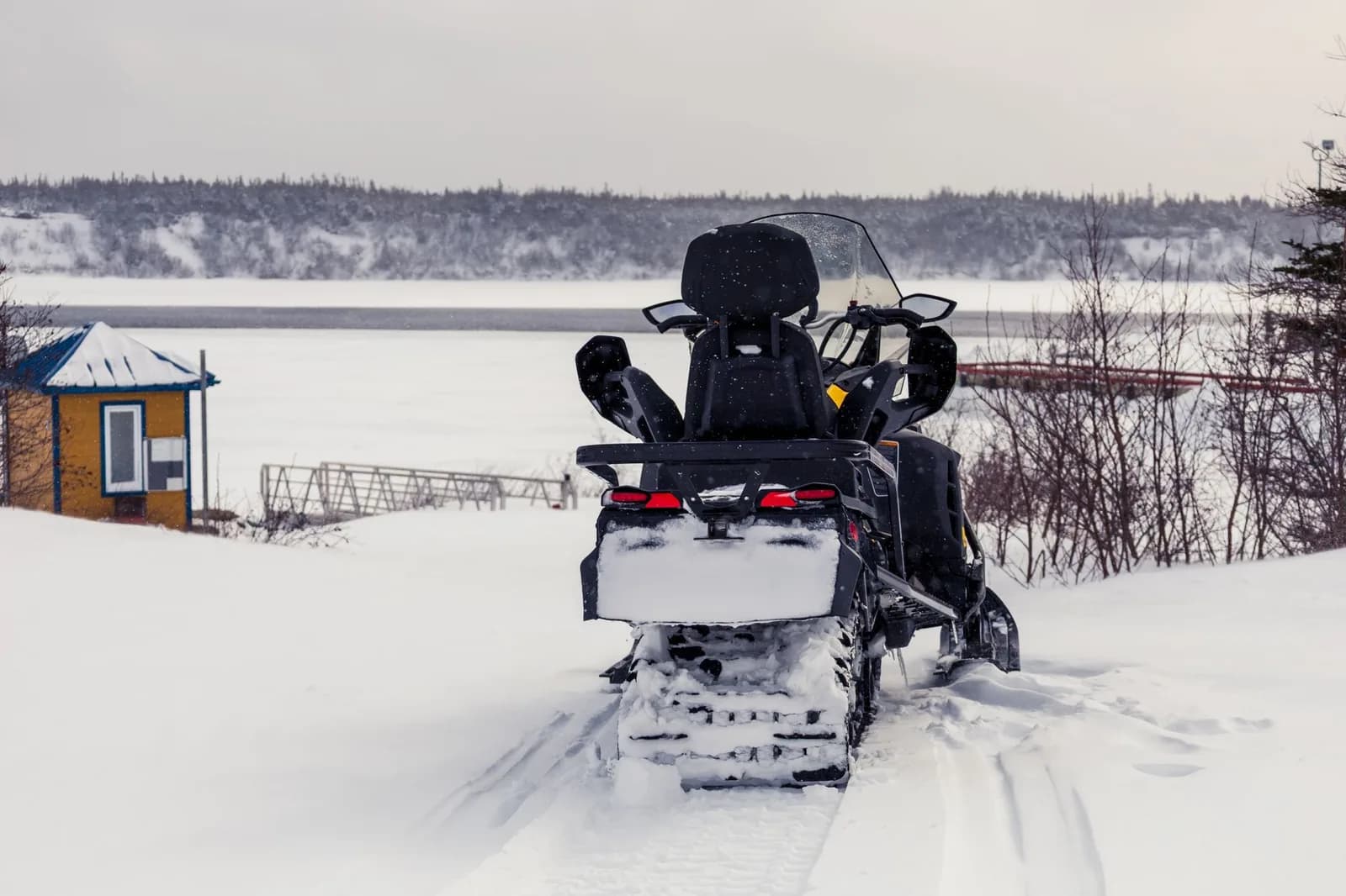Motoneige à l'arrêt sur une piste enneigée au bord d'un lac gelé